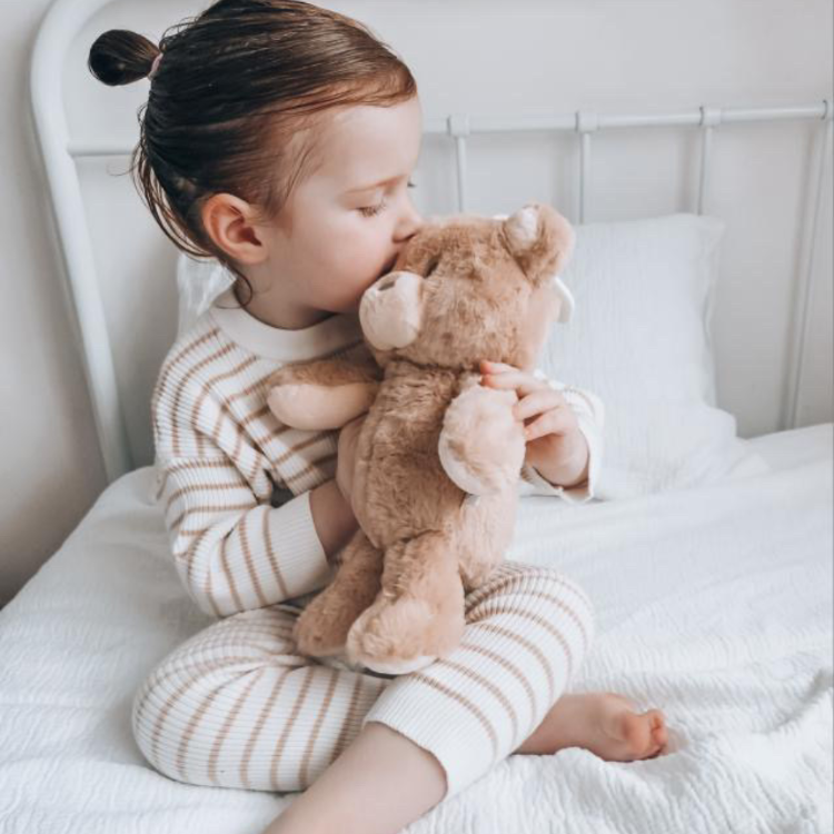 Toddler hugging sleep toy affirmation teddy bear during bedtime routine